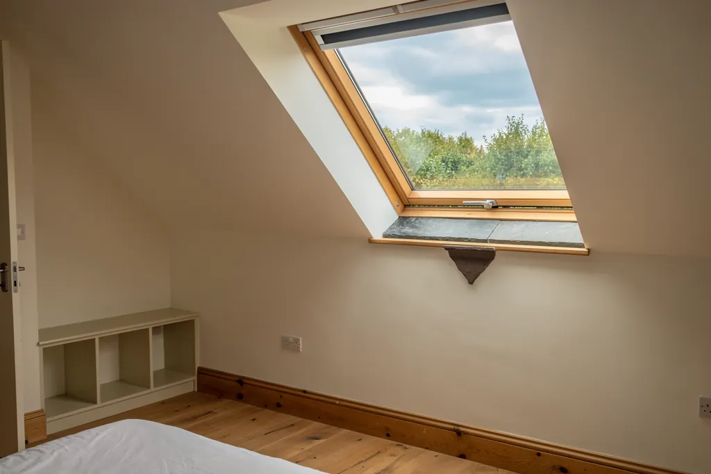 An open top-hung roof window in a loft bedroom